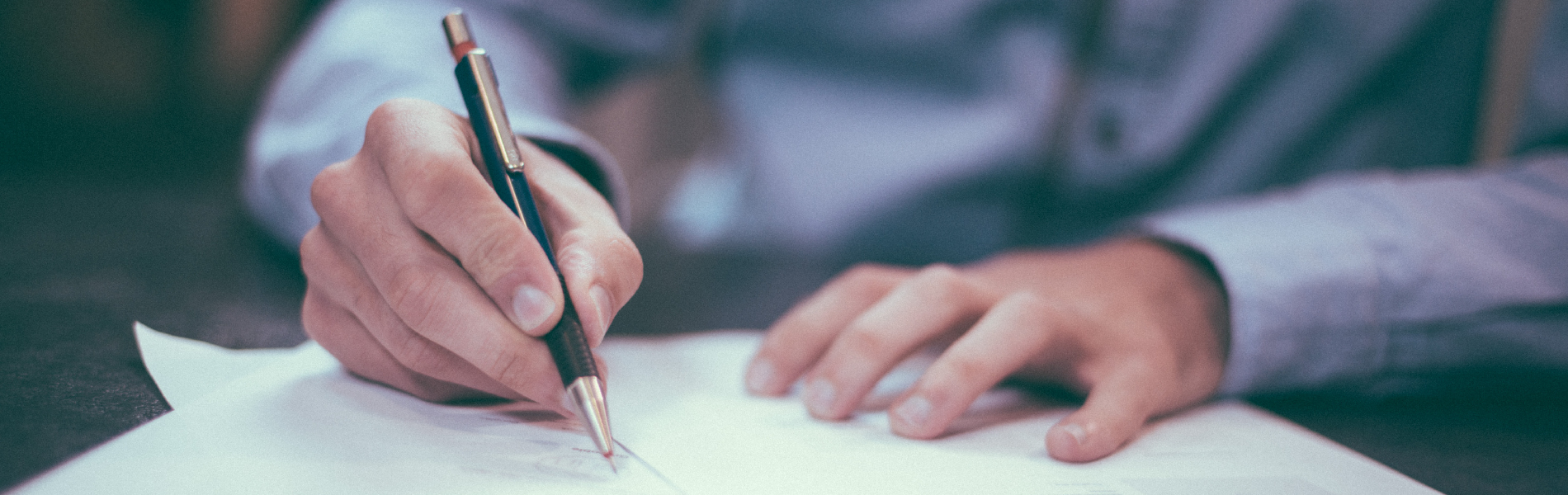 Hand holding a pen writing on a document